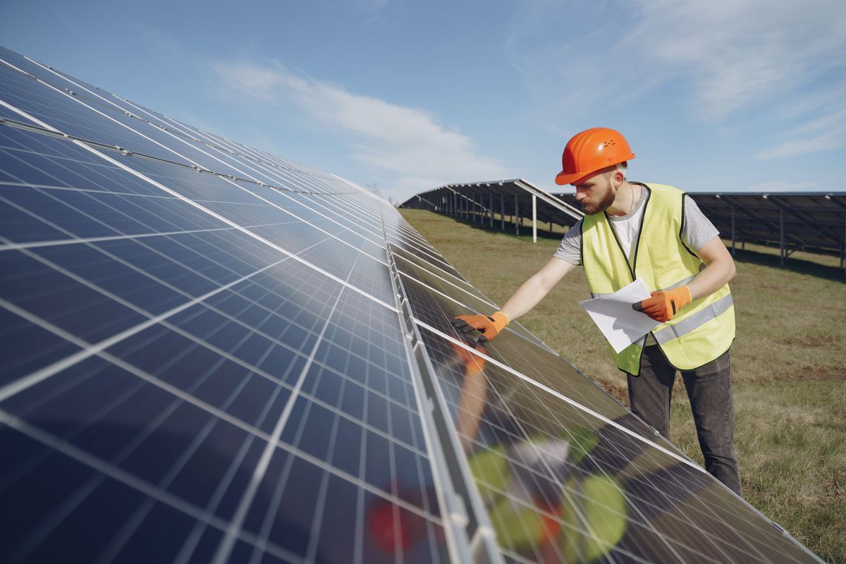 Engineer inspecting photovoltaic panels at a solar farm