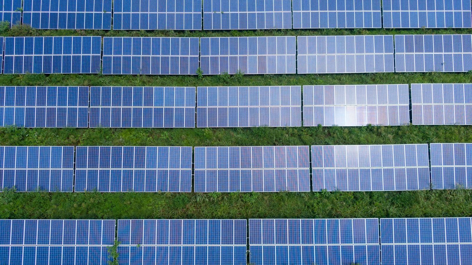 Aerial view of rows of photovoltaic modules in a ground-mounted solar park